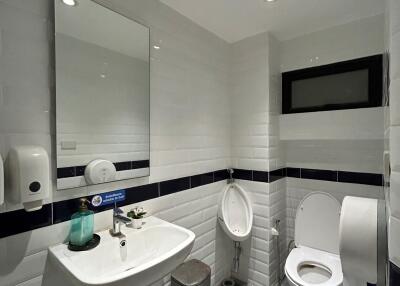 Modern clean bathroom with white and navy blue tiles, featuring a toilet, sink, and mirror