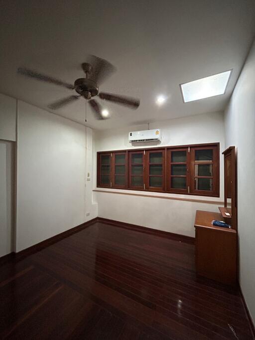 Spacious bedroom with hardwood flooring, ceiling fan, and air conditioning unit