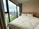 Bright bedroom with a large bed and a panoramic city view