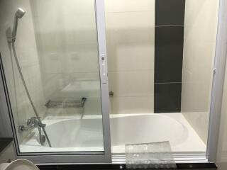Modern bathroom with glass shower door and white bathtub