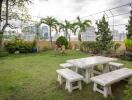 Spacious garden area with green lawn, seating arrangement, and a backdrop of an urban skyline