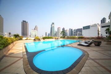 Spacious outdoor swimming pool with city skyline view and lounge chairs