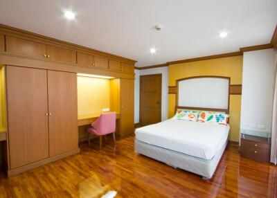 Spacious bedroom with wooden flooring and ample lighting