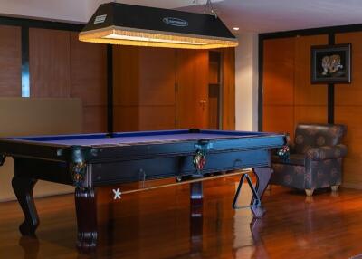 Elegant recreation room with a blue billiard table, hardwood floors, and a cozy seating area