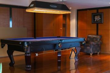 Elegant recreation room with a blue billiard table, hardwood floors, and a cozy seating area