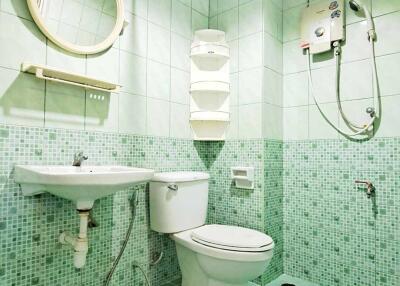 Compact bathroom with green tile flooring and walls, equipped with modern amenities