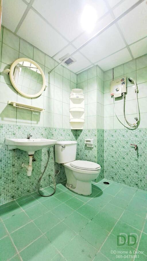 Compact bathroom with green tile flooring and walls, equipped with modern amenities