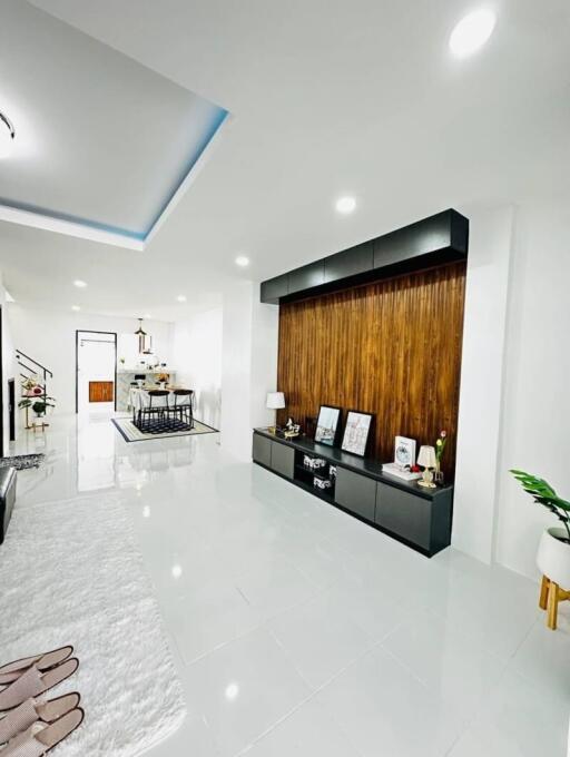 Spacious and modern living room interior with polished white floor tiles and wooden accent wall