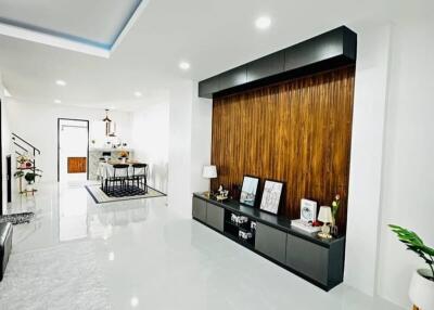 Spacious and modern living room interior with polished white floor tiles and wooden accent wall