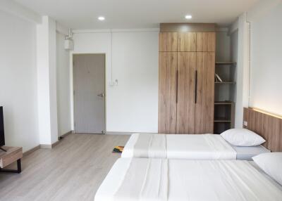 Spacious modern bedroom with a wooden wardrobe and attached shelving units
