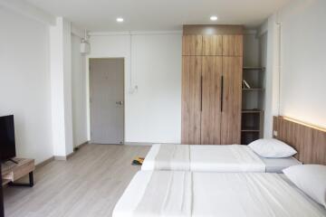 Spacious modern bedroom with a wooden wardrobe and attached shelving units