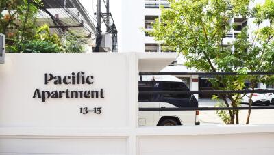 Entrance of Pacific Apartment with visible signage and part of the street