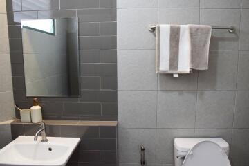 Modern bathroom with gray tiles, large mirror, and white fixtures