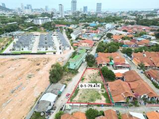 Aerial view of a residential area with a vacant plot of land outlined for sale