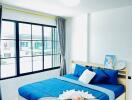 Bright and modern bedroom with large windows and cozy blue bedding