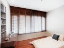 Modern bedroom interior with large window blinds, a comfortable bed, and wooden flooring