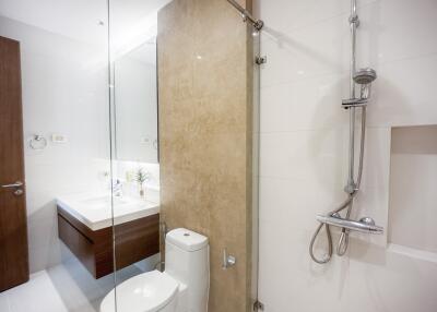 Modern bathroom interior with glass shower, wooden vanity, and white fixtures