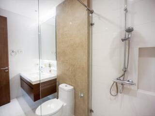 Modern bathroom interior with glass shower, wooden vanity, and white fixtures