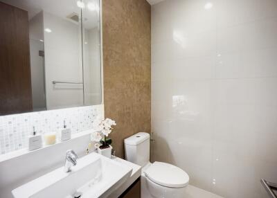 Modern bathroom with tiled walls, large mirror, and white fixtures