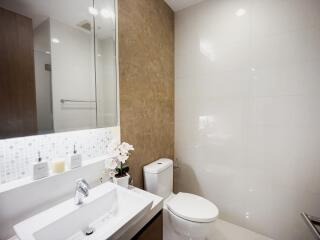 Modern bathroom with tiled walls, large mirror, and white fixtures