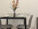 Compact dining table with modern chairs and decorative vase in a clean, minimalistic space