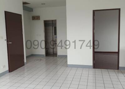 Spacious empty room with tiled flooring, multiple doors, and a ceiling fan