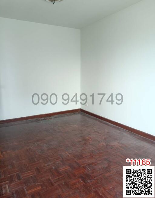 Empty bedroom with hardwood flooring and white walls