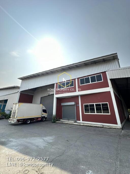 Two-story commercial building with a red facade and a parked delivery truck