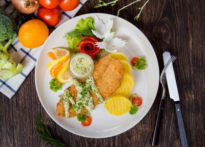 Well-presented meal on a dining table including vegetables and fish with a slice of lemon