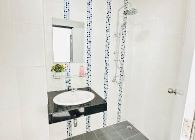 Modern bathroom with white and decorative tiles, featuring a walk-in shower and a sleek vanity basin