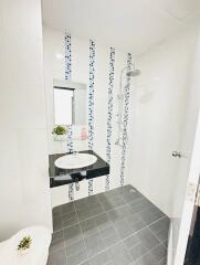 Modern bathroom with white and decorative tiles, featuring a walk-in shower and a sleek vanity basin