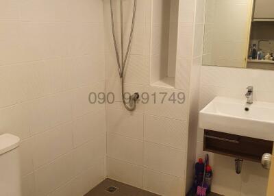 Compact bathroom with white wall tiles, shower, toilet, and sink