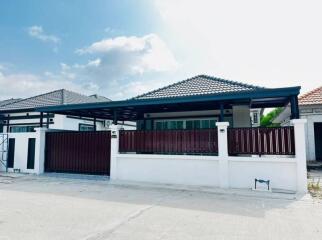 Front view of a residential house with a secure gate and carport