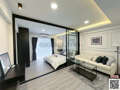 Modern bedroom with attached living area and large glass partition