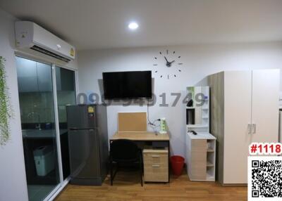 Compact bedroom with integrated workspace, refrigerator, and wall-mounted television