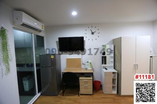 Compact bedroom with integrated workspace, refrigerator, and wall-mounted television