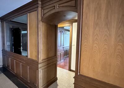 Elegant corridor with wood paneling and archway leading to additional rooms