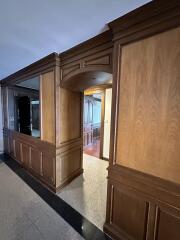 Elegant corridor with wood paneling and archway leading to additional rooms