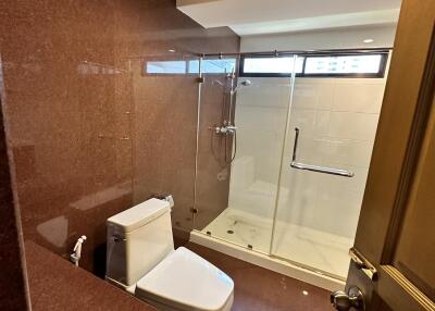 Modern bathroom with a glass shower enclosure and marble walls