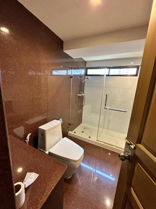 Modern bathroom with a glass shower enclosure and marble walls