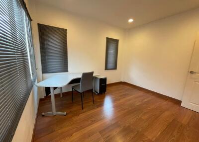 Spacious home office with large windows and hardwood flooring