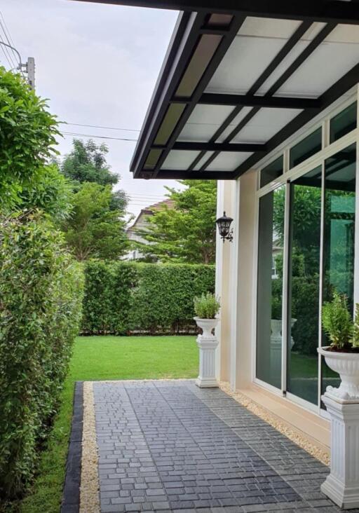 Paved pathway leading to a house with a manicured lawn and garden