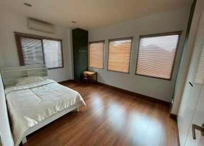 Spacious bedroom with wood flooring and natural light