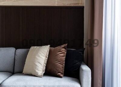 Cozy living room corner with a modern grey sofa, decorative pillows, elegant curtains, and a patterned floor