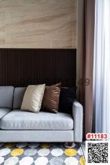 Cozy living room corner with a modern grey sofa, decorative pillows, elegant curtains, and a patterned floor