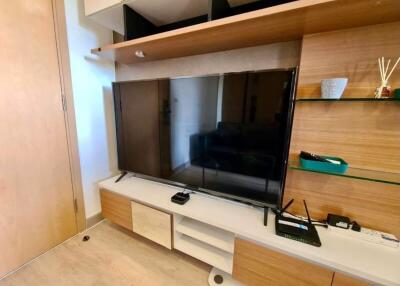 Modern living room interior with a large flat-screen TV and wooden shelving