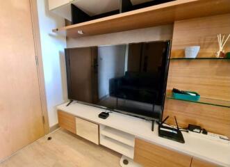 Modern living room interior with a large flat-screen TV and wooden shelving