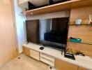 Modern living room interior with a large flat-screen TV and wooden shelving