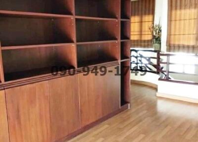 Spacious living room with large wooden bookshelf and balcony access