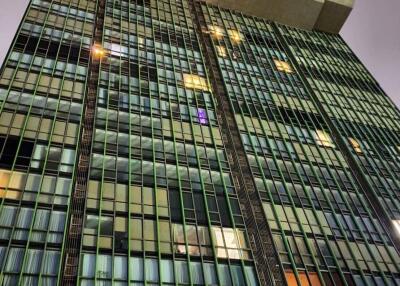 Low-angle view of a modern high-rise building at night with illuminated windows